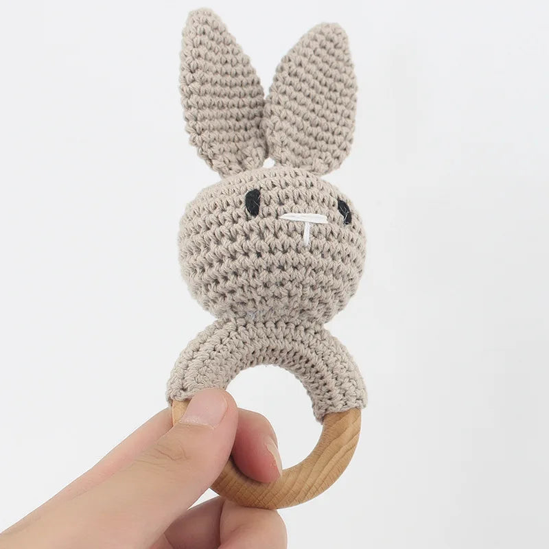 Crocheted bunny rattle held by a hand on a white background
