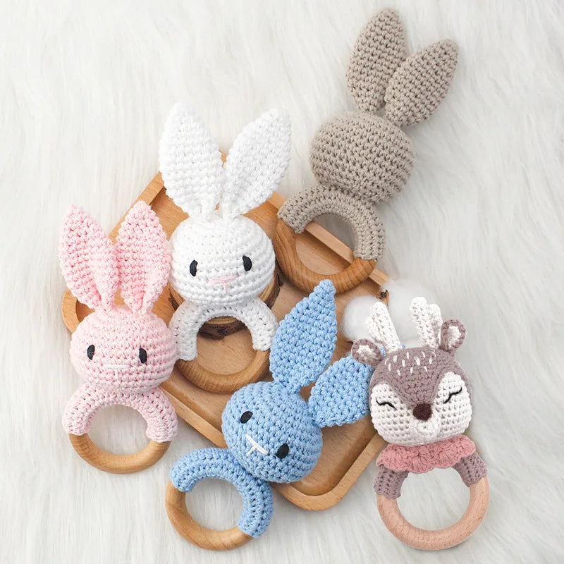 Set of crocheted rabbit-shaped baby teething rings in various colors on a wooden base.
